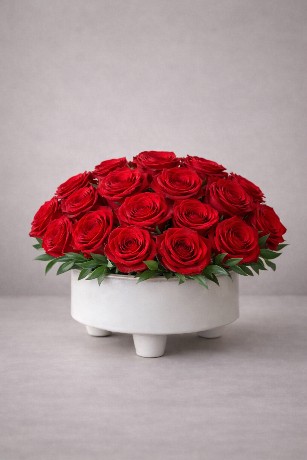 Bouquet of red roses in a white container on a light gray background